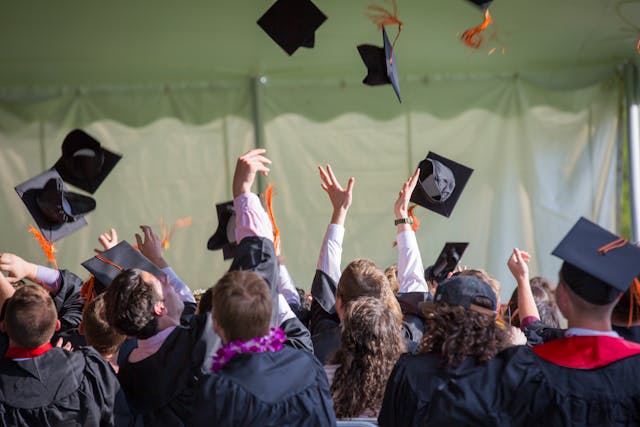 jóvenes lanzan birrete al aire en una graduación